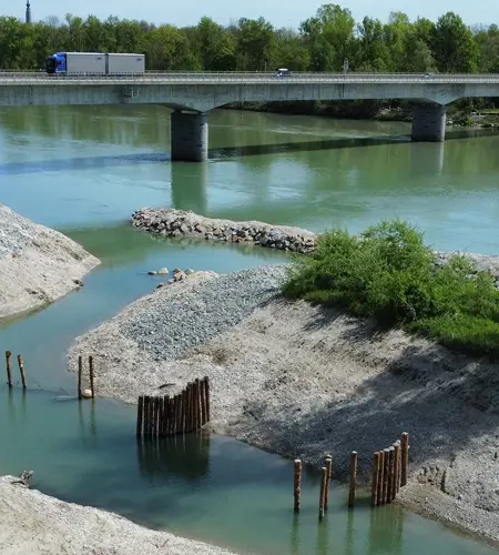 Aerial view of a bridge over a river with clear green water and gravel banks.